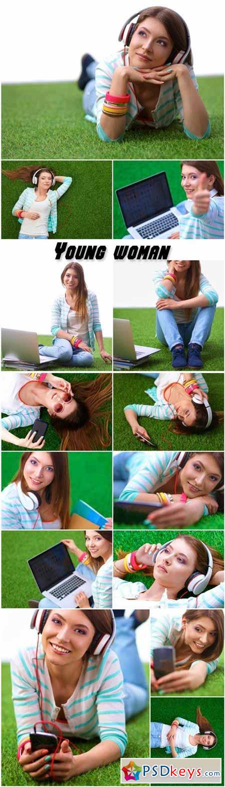 Beautiful young woman with a phone and a laptop on the green grass