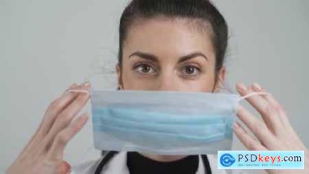 Young Female Doctor Puts Face Mask on Mouth and Nose Protective Measures Against COVID-19 Close 26066280