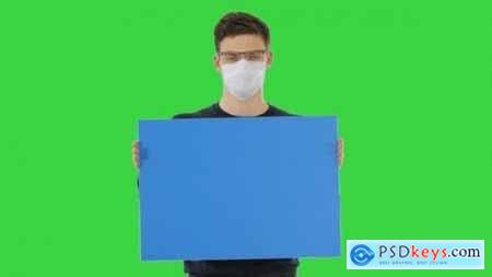 Young Man in Medical Mask Showing and Displaying Placard on a Green Screen Chroma Key 26313180